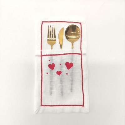 Talheres dourados sobre guardanapo branco com corações vermelhos