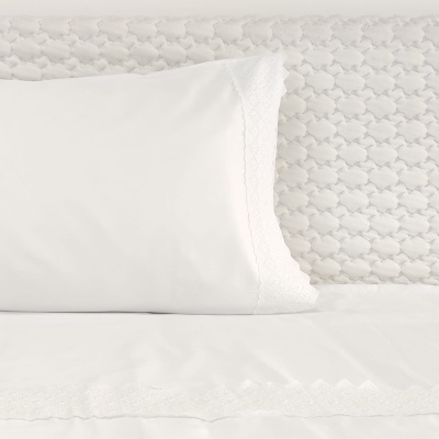 Roupas de cama brancas com renda e colchão acolchoado em fundo claro