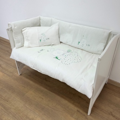 Sofá branco com capas almofadadas bordadas e chão de madeira.