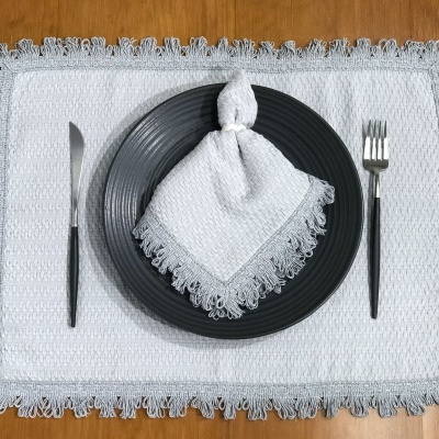 Conjunto de mesa com individual branco, prato preto, guardanapo branco e talheres