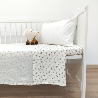 Berço branco com roupa de cama branca e peluche de vaca