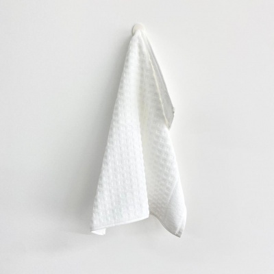 Toalha branca com textura pendurada numa parede branca
