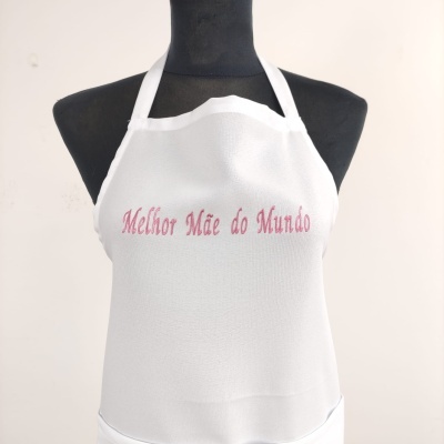 Avental branco com texto 'Melhor Mãe do Mundo' em tecido sobre manequim preto