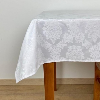 Toalha de mesa branca com padrão damasco em relevo sobre mesa de madeira