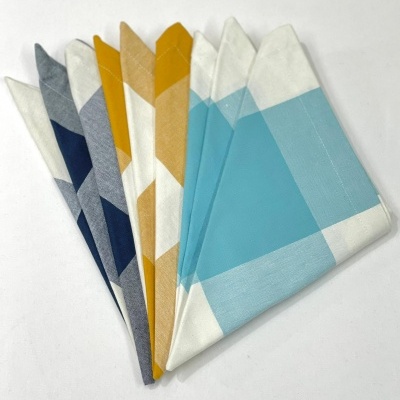 Guardanapos de tecido com padrão de quadrados coloridos em azul, cinzento, amarelo e branco