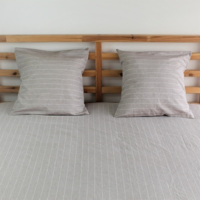 Cama com almofadões cinza risca fina e cabeceira de madeira clara