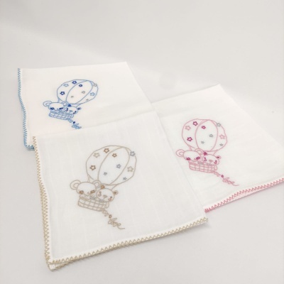 Três panos de tecido branco com bordados de balões e ursinhos em azul, bege e rosa.