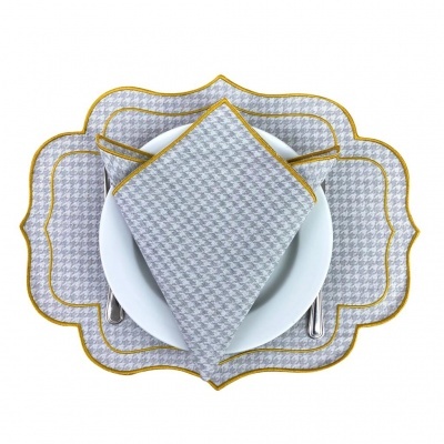 Conjunto de guardanapo e toalhinha cinza com padrão pied-de-poule e detalhe amarelo sobre prato branco