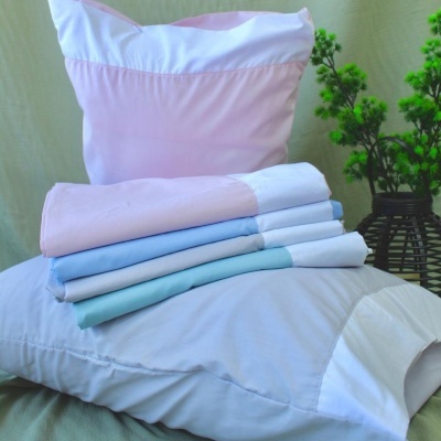 Conjunto de roupa de cama colorida sobre almofadas e planta ao fundo