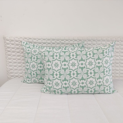 Três almofadas decorativas estampadas em cama branca.