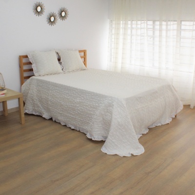 Quarto com cama de madeira clara e colcha branca, mesa de madeira com planta, paredes e cortinas brancas