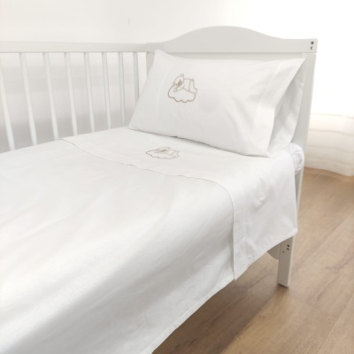 Lençol e fronha brancos com bordados de ursinho numa cama branca