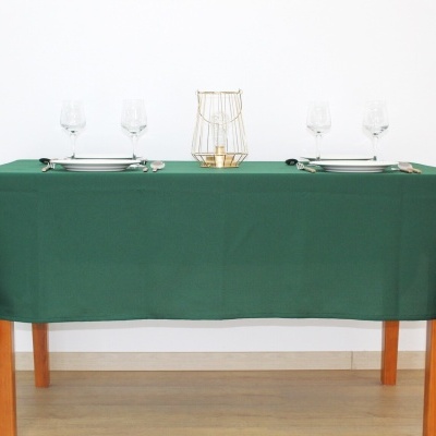 Mesa com toalha verde, copos de vidro, talheres prateados e suporte decorativo dourado