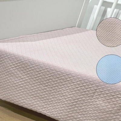 Colcha matelassada rosa claro sobre cama branca com amostras de textura em rosa e azul