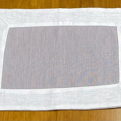Toalhete retangular cinzento com moldura branca sobre superfície de madeira