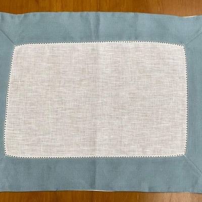 Individual rectangular branco com borda azul claro sobre superfície de madeira