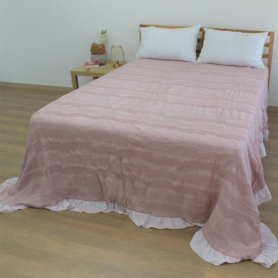 Colcha cor-de-rosa com faixa branca em cama de madeira clara num quarto minimalista