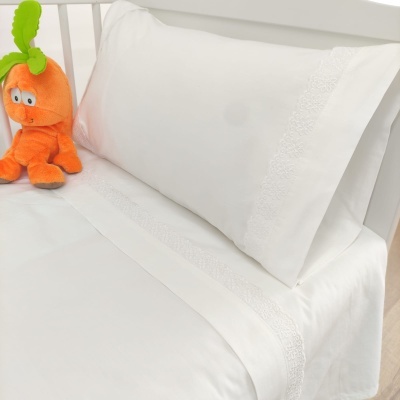Roupas de cama brancas detalhadas com bordados e peluche laranja em forma de cenoura