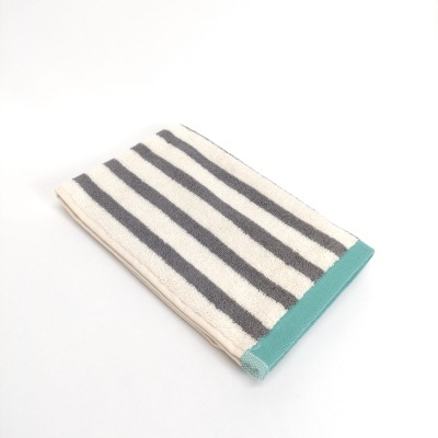 Toalha de algodão com riscas cinzentas e borda verde dobrada