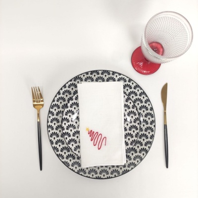 Conjunto de jantar com prato decorado, talheres e copo com base vermelha.