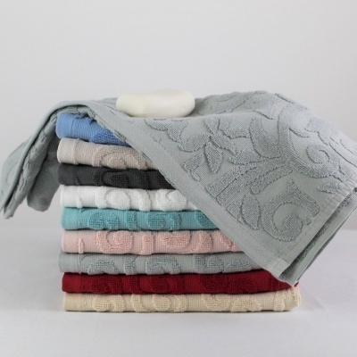 Conjunto de toalhas coloridas com textura floral e barra de sabão em cima