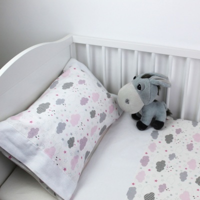 Cama de criança com lençol e fronha de nuvens e peluche de burro