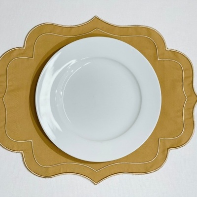 Prato branco redondo sobre individual amarelo mostarda com bordas onduladas.