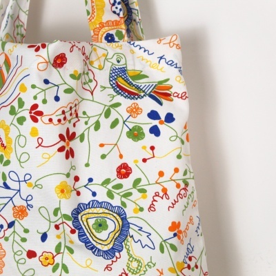 Saco de tecido branco com estampa colorida de flores e pássaro