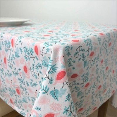 Toalha de mesa floral em azul, verde e rosa coral numa mesa de madeira clara.