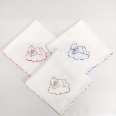 Três fraldas de pano brancas com ursinhos bordados em rosa, azul e bege.