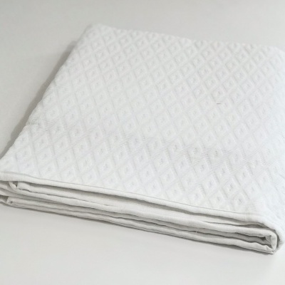 Manta branca dobrada com padrão geométrico em relevo