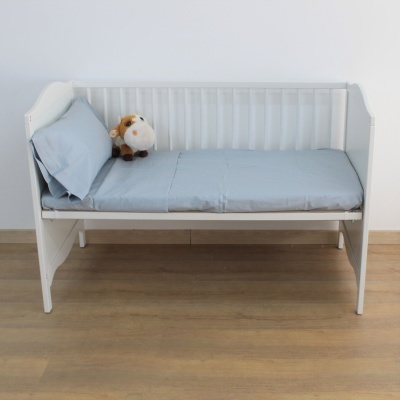 Berço branco com colchão azul, almofada e peluche de vaca