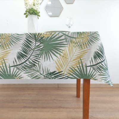 Toalha de mesa com padrão de folhas verdes e amarelas sobre mesa de madeira