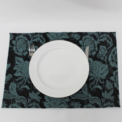 Prato branco redondo sobre guardanapo floral com garfo e faca