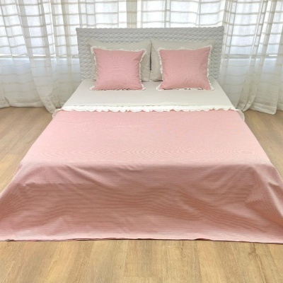 Cama de casal decorada com colcha rosa e almofadas em quarto claro
