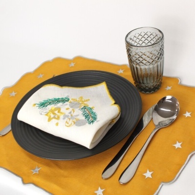 Conjunto de jantar com prato cinza, copo de vidro, talheres prateados, guardanapo bordado e toalha amarela com estrelas