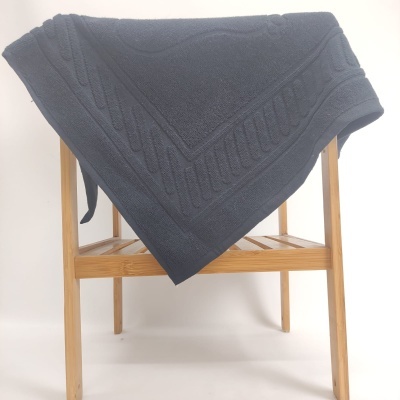 Manta cinzenta escura com padrão trançado sobre estrutura de madeira clara