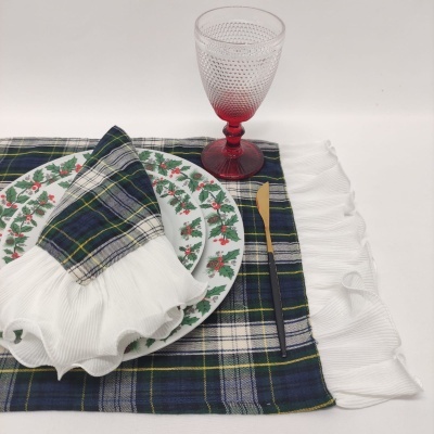 Prato decorado com motivos de frutas vermelhas, guardanapo tartan azul e branco, talheres dourados e copo vermelho texturizado