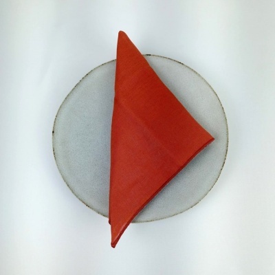 Prato cinza claro com guardanapo vermelho dobrado no centro