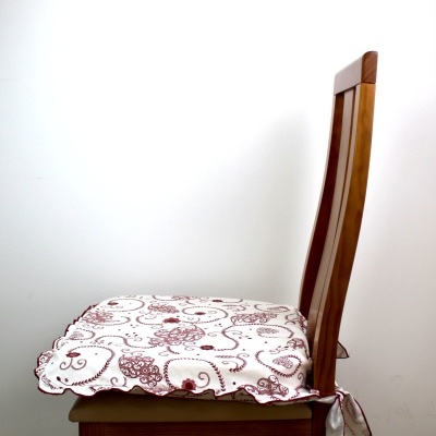 Cadeira de madeira com almofada branca estampada com flores vermelhas