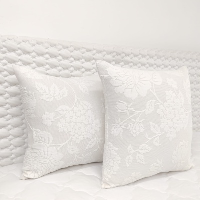 Duas almofadas quadradas brancas com padrão floral em relevo