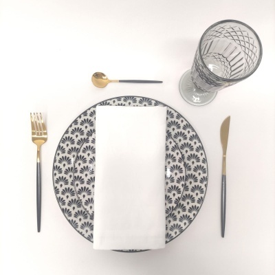 Conjunto de louça preto e branco com talheres dourados e copo transparente