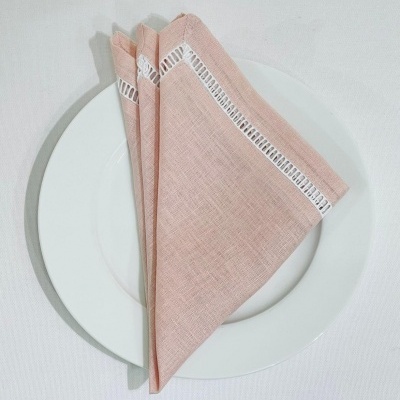 Guardanapo de tecido cor de rosa claro dobrado sobre prato branco