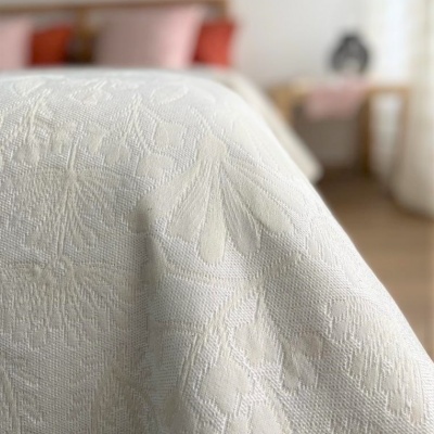 Toalha branca com padrão floral texturizado em ambiente de quarto