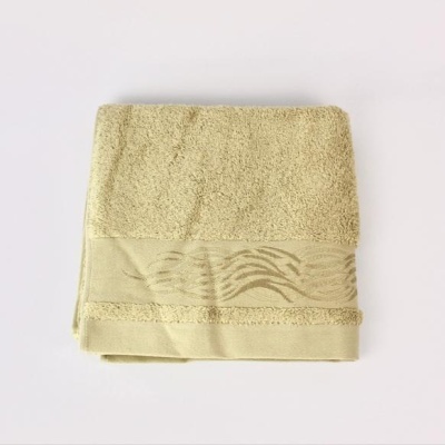 toalha de banho amarelo claro dobrada com faixa decorativa em padrão abstrato