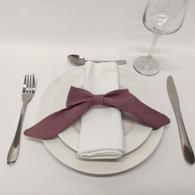 Conjunto de mesa com prato branco, talheres, guardanapo com laço vinho e copo de vidro