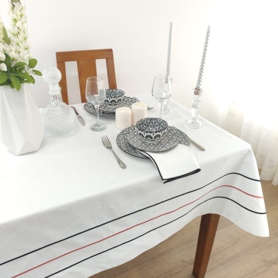 Toalha de mesa branca com pratos azuis e brancos, velas e vaso com flores