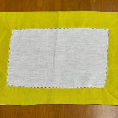 Guardanapo amarelo e branco com costura preta sobre mesa de madeira