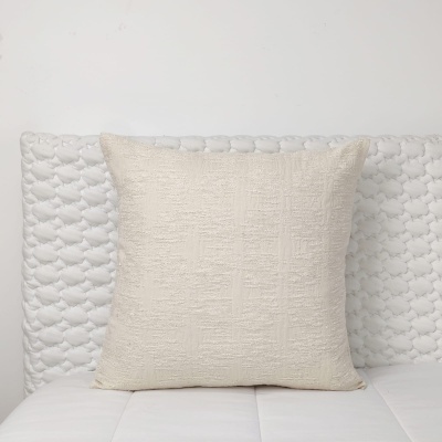 Almofada beige texturada num sofá branco acolchoado