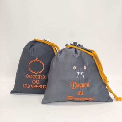 Dois sacos cinza com cordão amarelo e texto laranja, decoração temática de Halloween.